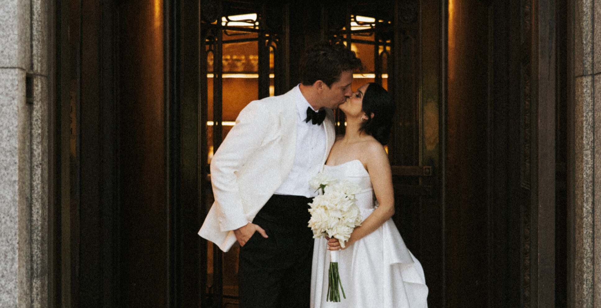 Bride and groom kissing in front of the Trust