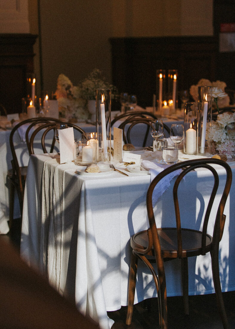 Reception tablescape with white florals, menus and lit candles