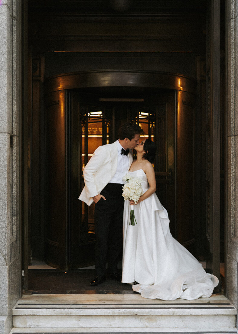 Wedding couple pose in front of the the revolving doors at The Trust